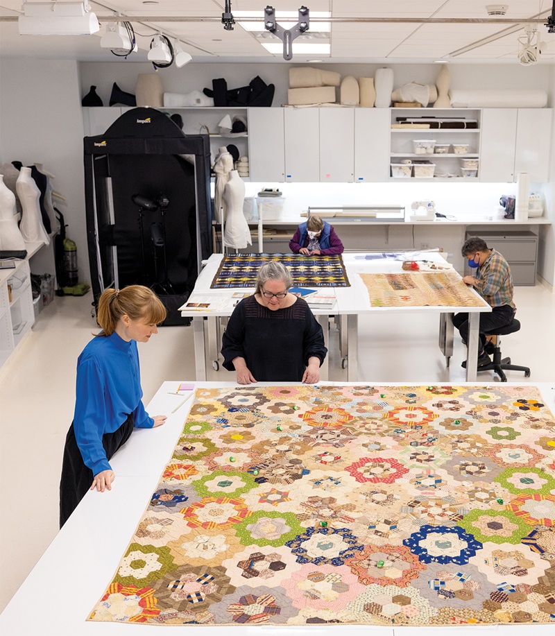 Marina Moskowitz and Sophie Pitman examine a quilt by Julia Morris Jackson (Q.P.US.0151) in the Helen Louise Allen Textile Collection workroom, while Sandy Winder and Lars Shimabukuro stabilize quilts (Q.P.US.0009 and Q.P.US.0024) for display. Photo by Sharon Vanorny, courtesy of the Nancy M. Bruce Center for Design and Material Culture. Marina Moskowitz and Sophie Pitman examine a quilt by Julia Morris Jackson (Q.P.US.0151) in the Helen Louise Allen Textile Collection workroom, while Sandy Winder and Lars Shimabukuro stabilize quilts (Q.P.US.0009 and Q.P.US.0024) for display. Photo by Sharon Vanorny, courtesy of the Nancy M. Bruce Center for Design and Material Culture.