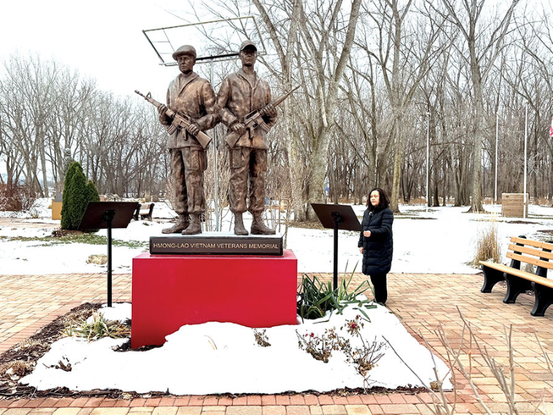 The author standing next to the Hmong-Lao Vietnam Veterans Memorial in La Crosse. Credit: Flashe Yang.