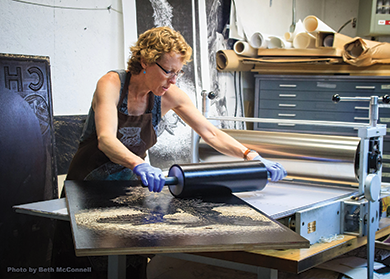 SV Medaris rolls ink on a large woodcut in her studio. Photo by Beth McConnell. 