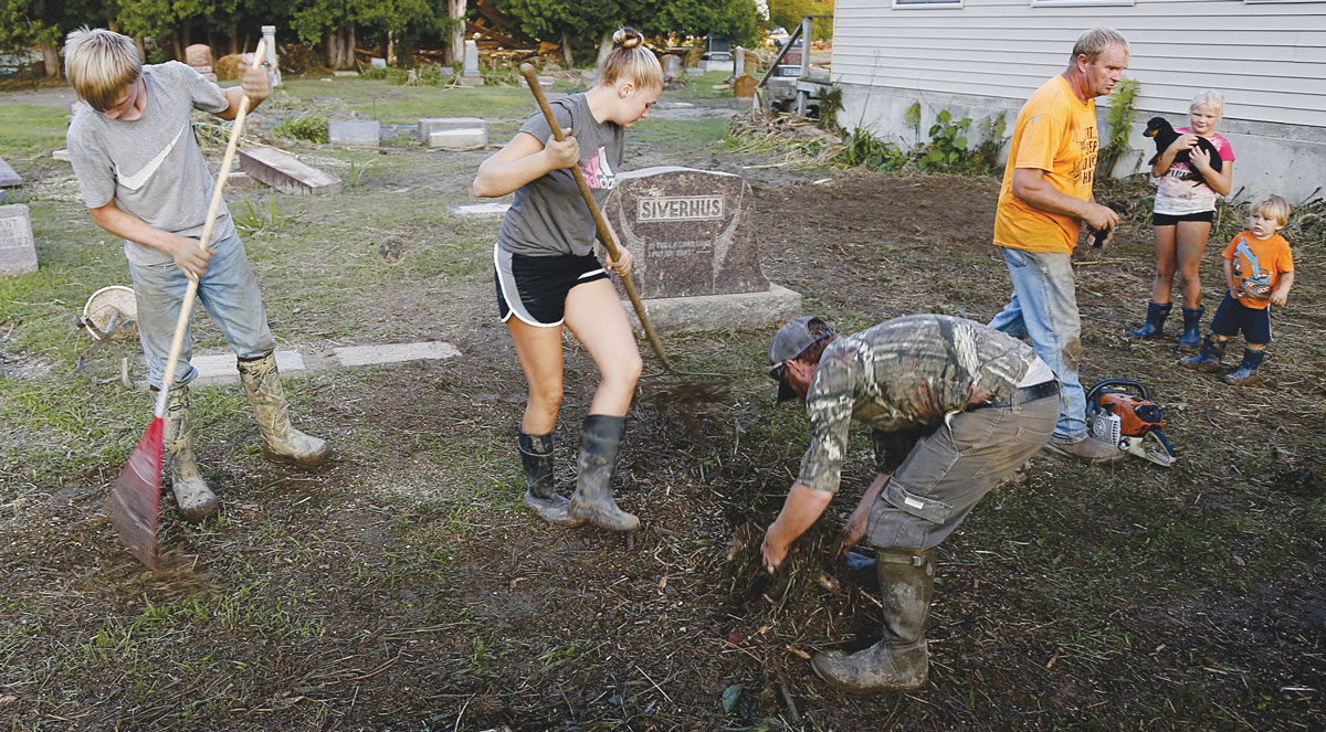 The Siverhus Family, pioneers of Rullands Coulee near Coon Valley, clean up the Skogdalen Cemetery two days after a massive flood ripped through, tipping gravestones. Photo by Jon Lee.