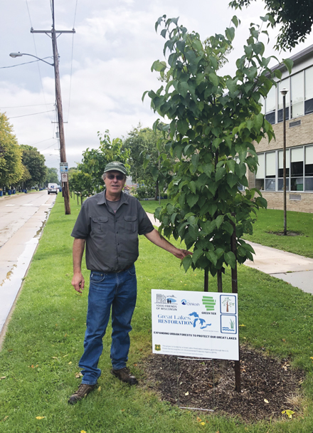 Bill Sturm, Oshkosh City Forester & Landscape Operations Manager, stands in front of a young redbud tree planted by the city to help capture rainfall. Sturm’s work is part of a larger, statewide initiative through 1000 Friends of Wisconsin that draws on a U.S. Forest Service grant through the Great Lakes Restoration Initiative to reduce runoff and improve water quality. Photo credit: Abe Lenoch/1000 Friends of Wisconsin.