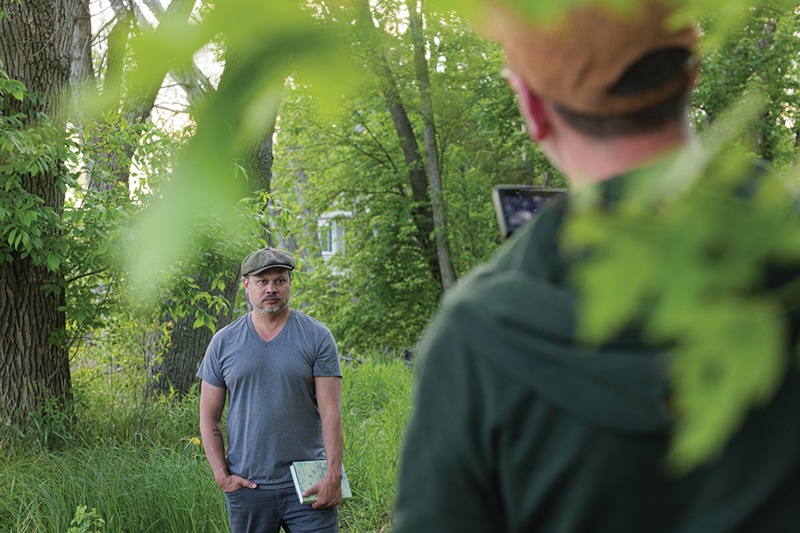 PBS Wisconsin videographer Zack Whitford captures footage of Nicholas Gulig on the banks of the Rock River near the small cabin where Lorine Niedecker lived in Fort Atkinson.