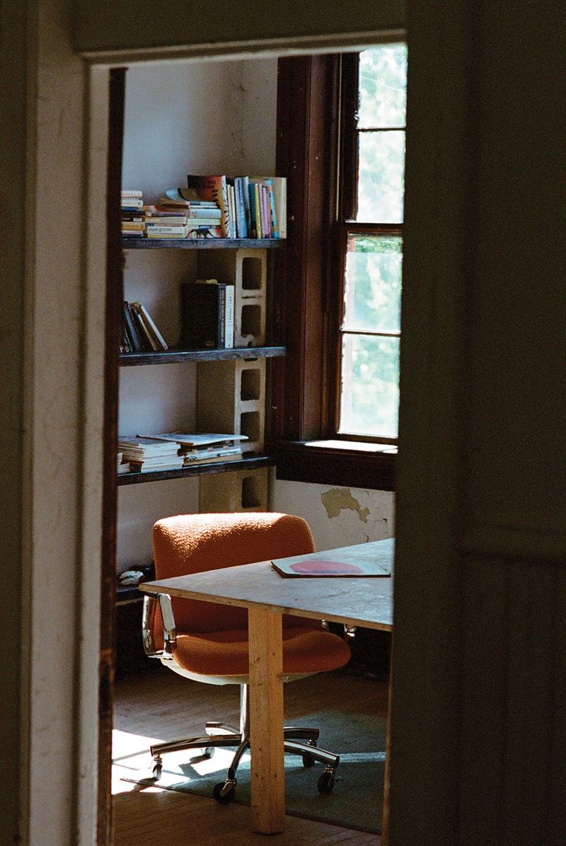 A chair and makeshift cinder block bookshelf are visible through a doorway inside Poor Farm Experiment