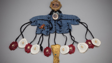 Marna Brauner. Not So Much Sin as Folly. 2025. Dyed antique textile and buttons, digital photograph, cast wax, doll hair, antique doll glove, celluloid teeth, notions. 1 inch H x 17 inches W x 14 inches.